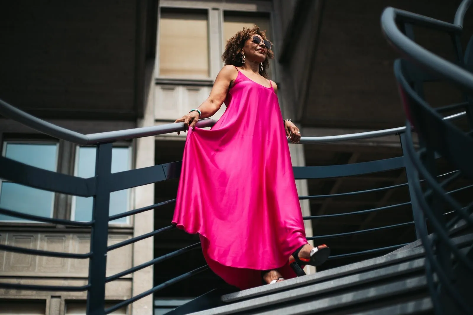 Woman in a pink dress on a city staircase, photographed from below